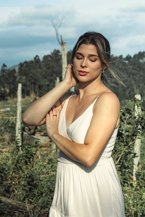 A woman in a white dress is standing in a field