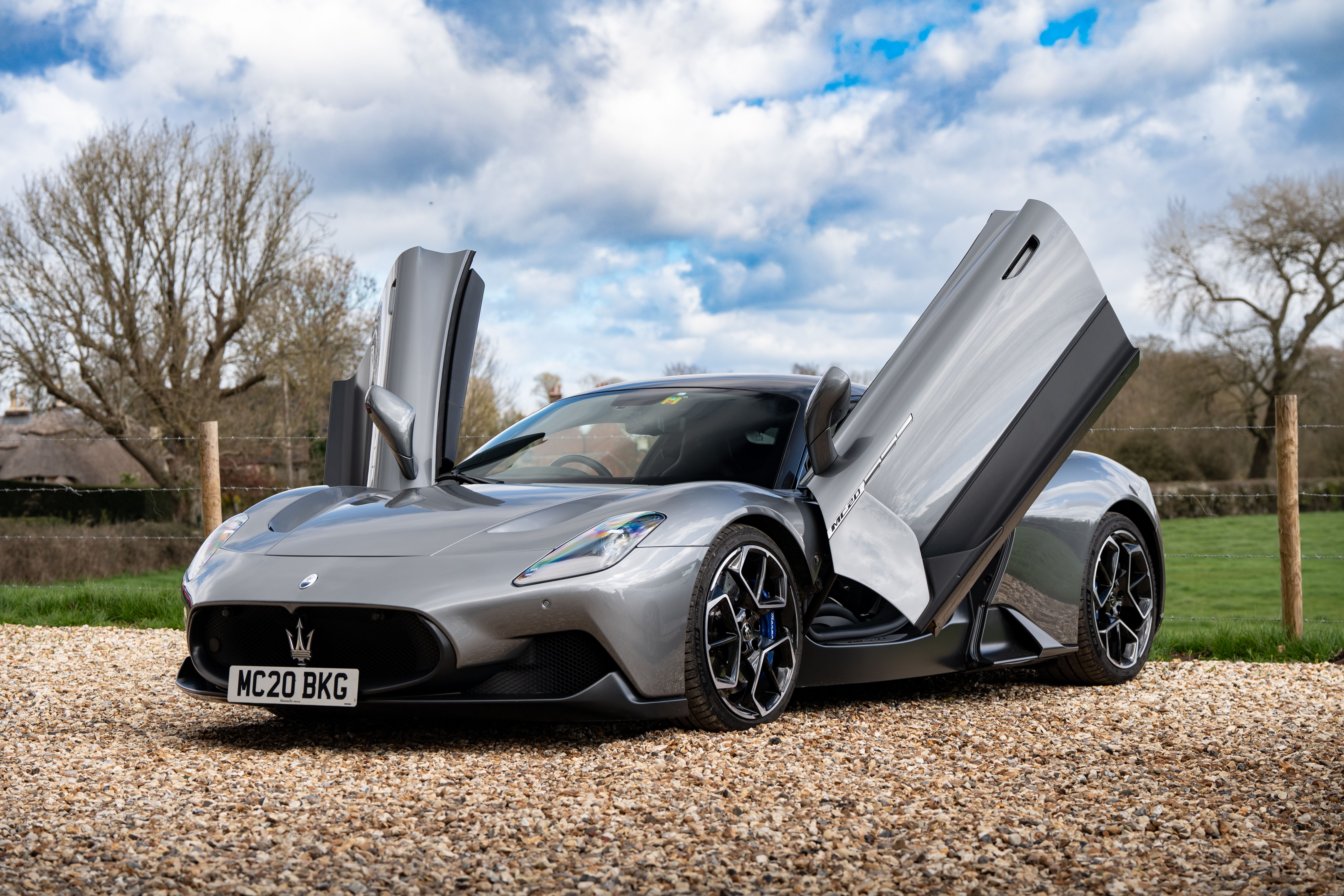 Maserati sports car with butterfly doors parked in a rural English setting.