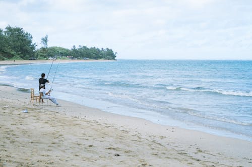 Free A person sitting on a chair on the beach Stock Photo