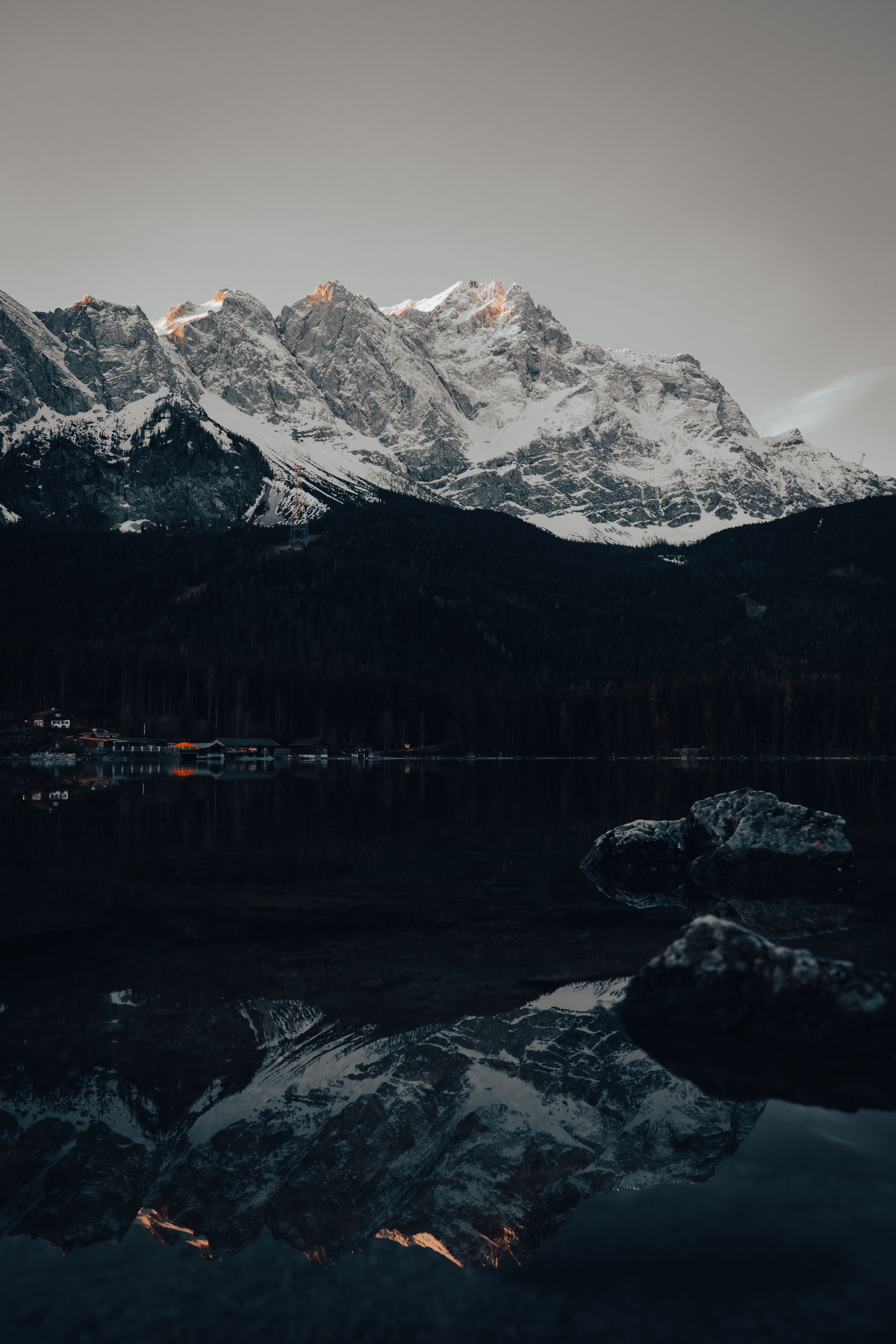 Stunning snowy mountain landscape reflected in a tranquil lake at twilight in Grainau, Germany.