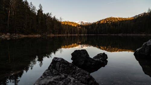 A lake surrounded by rocks and trees at sunset