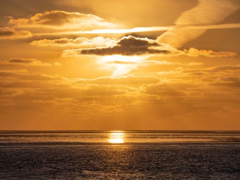 A stunning golden sunset casting warm hues over the calm ocean horizon.