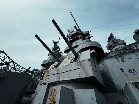 Close-up view of USS Alabama battleship's deck and cannons under a clear sky.
