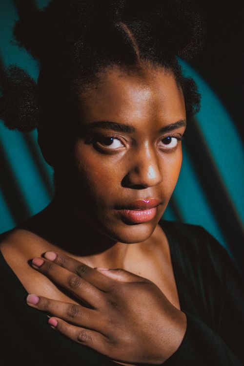 Free Captivating portrait of a black woman with natural hairstyle, set against a dramatic studio backdrop. Stock Photo