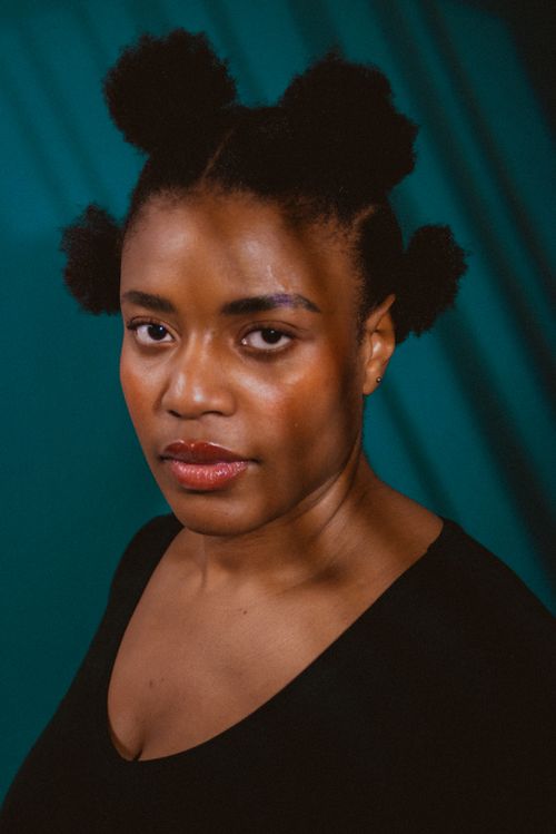 Free Artistic portrait of a woman with afro puffs against a blue background in studio lighting. Stock Photo