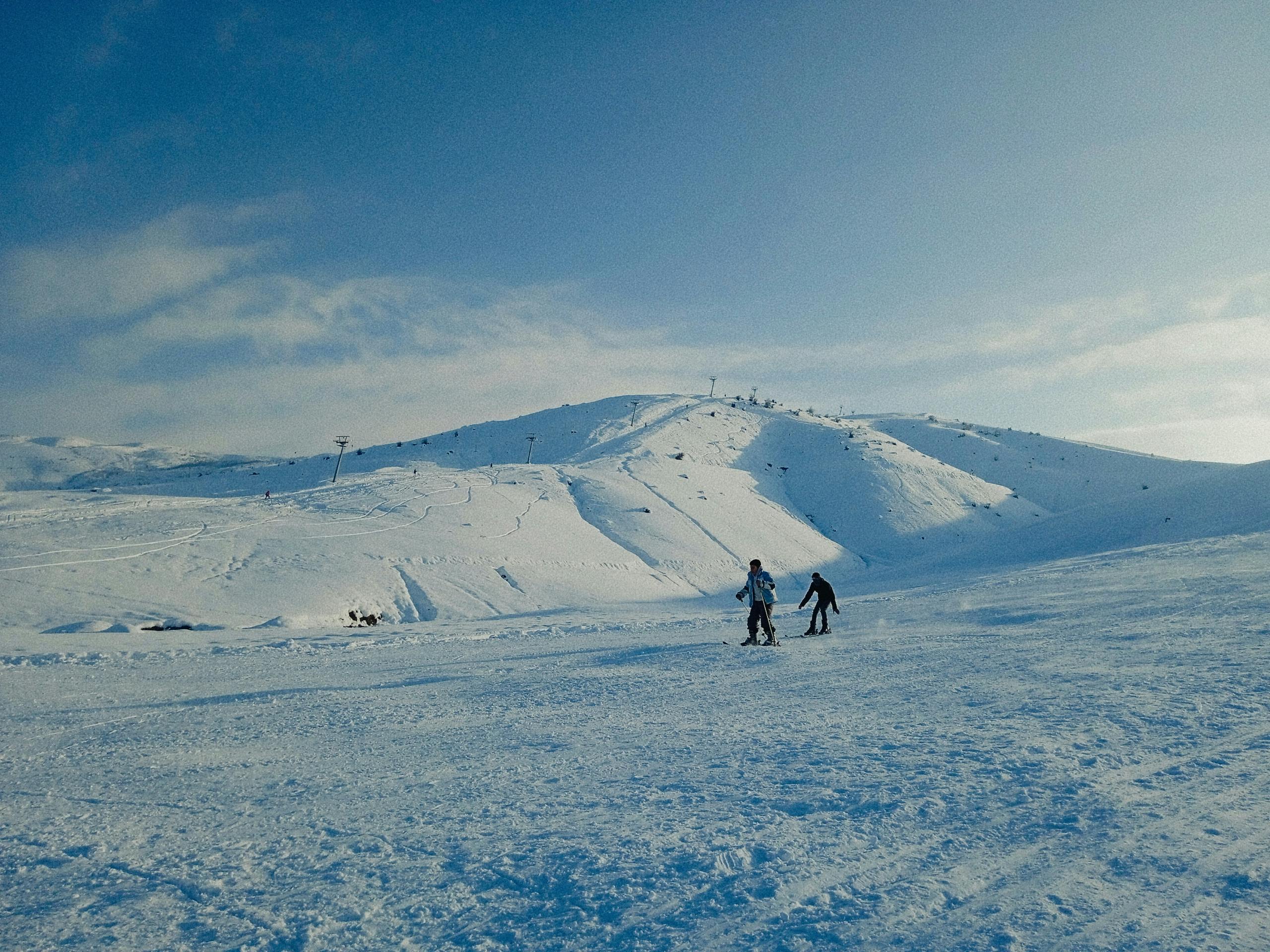 Prescription Goggle Inserts - Two people skiing on a sunny day on a snow-covered mountain, perfect for a winter adventure.