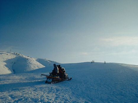 Capture of a snowmobile ride across snowy hills under a clear winter sky, perfect for adventure lovers.