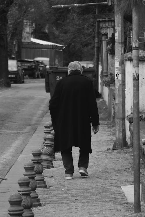 Free A man walking down the street in a black and white photo Stock Photo