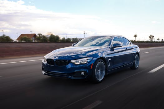 A dynamic shot of a blue luxury coupe cruising down a highway under a clear sky.