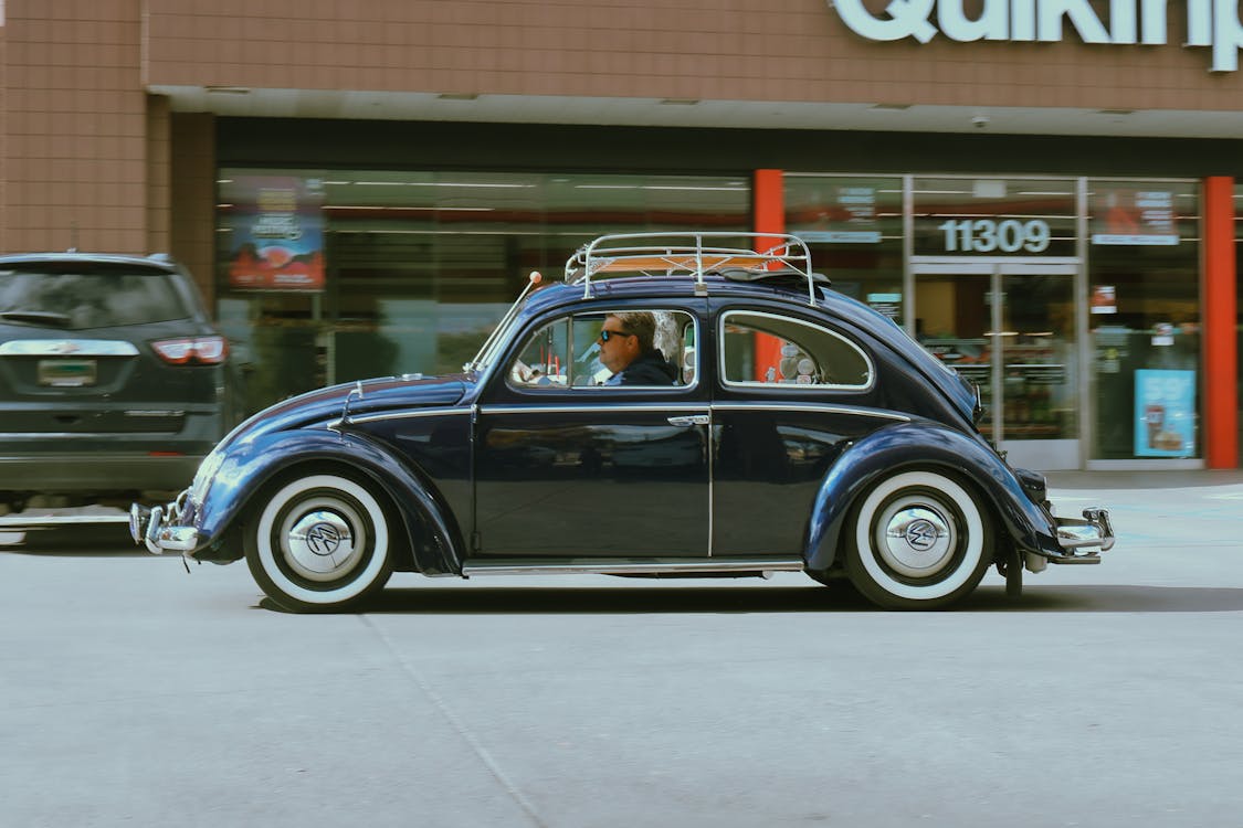 A blue volkswagen beetle is parked in front of a store