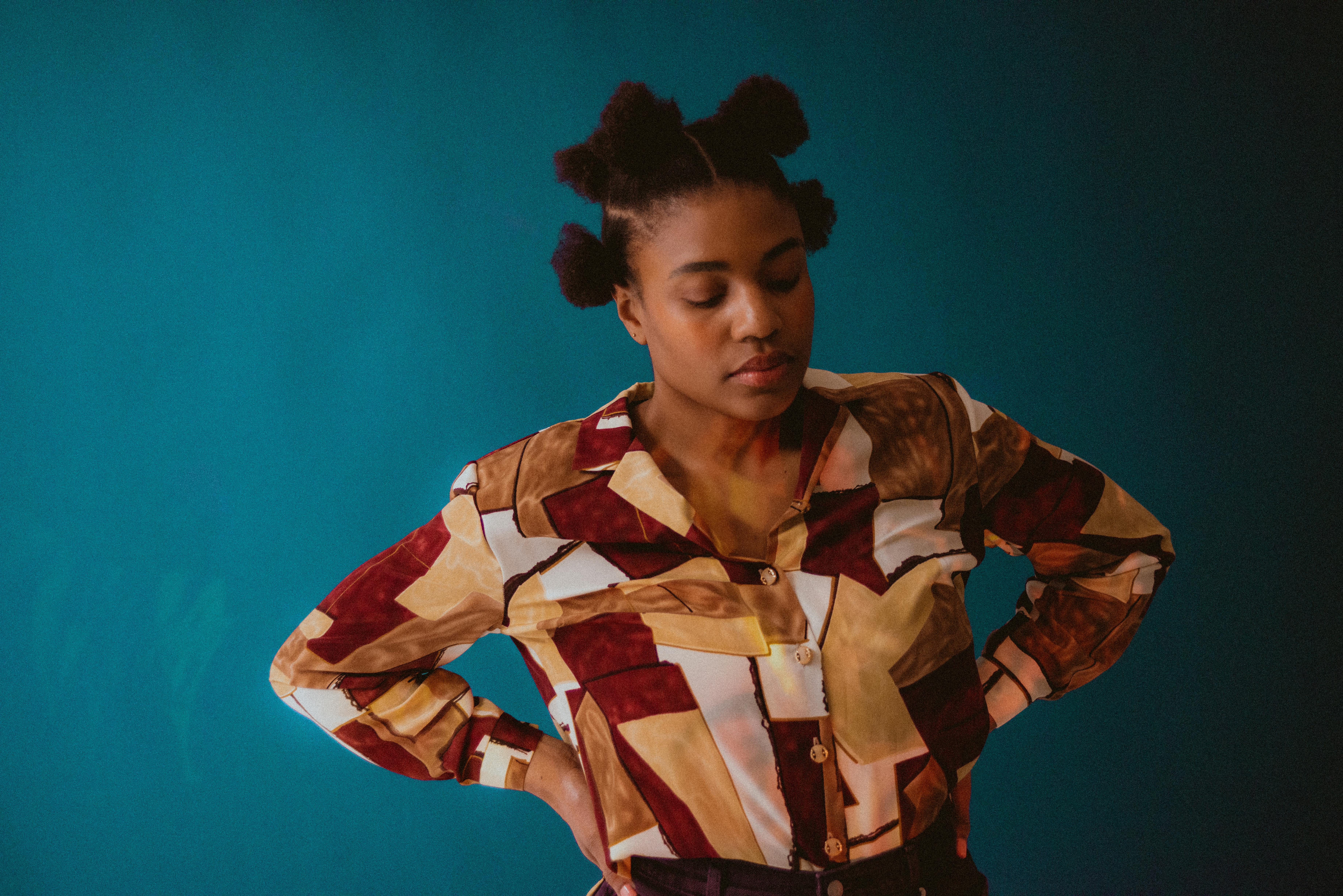 Portrait of a stylish woman posing with a geometric shirt against a solid background.