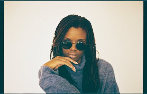 A woman with dreadlocks wearing sunglasses and a sweater