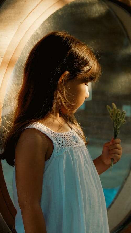 A little girl holding a flower in front of a mirror