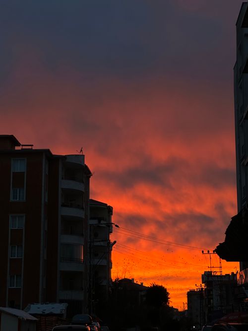Free Captivating sunset over a cityscape with fiery orange clouds and building silhouettes. Stock Photo