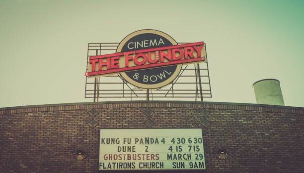 Old cinema facade featuring a classic sign and movie marquee listings.
