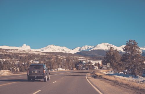 Free SUV driving along a snow-covered mountain highway under clear blue skies in winter. Stock Photo