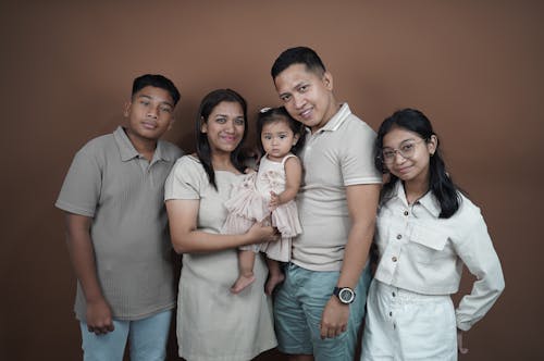 A family poses for a photo in front of a brown background