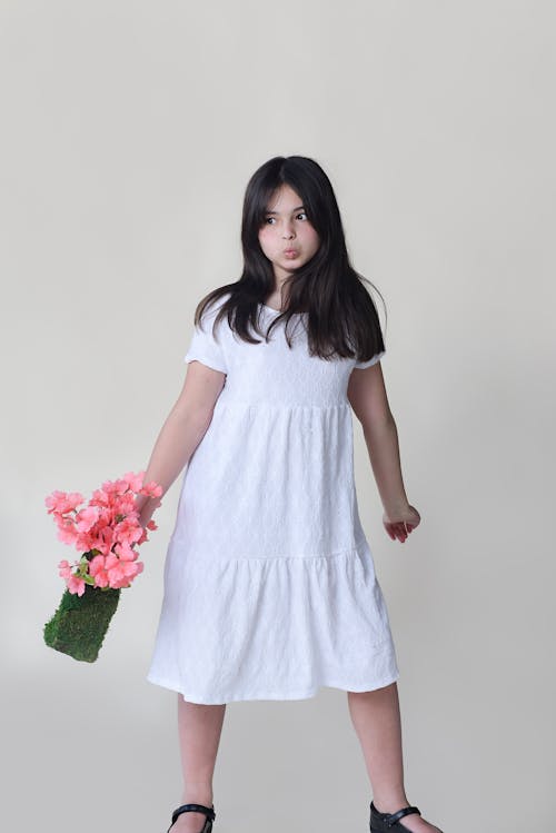 A girl in a white dress holding flowers