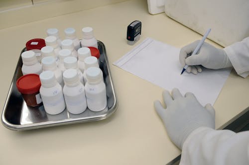 Person in White Hand Gloves Writing on White Paper