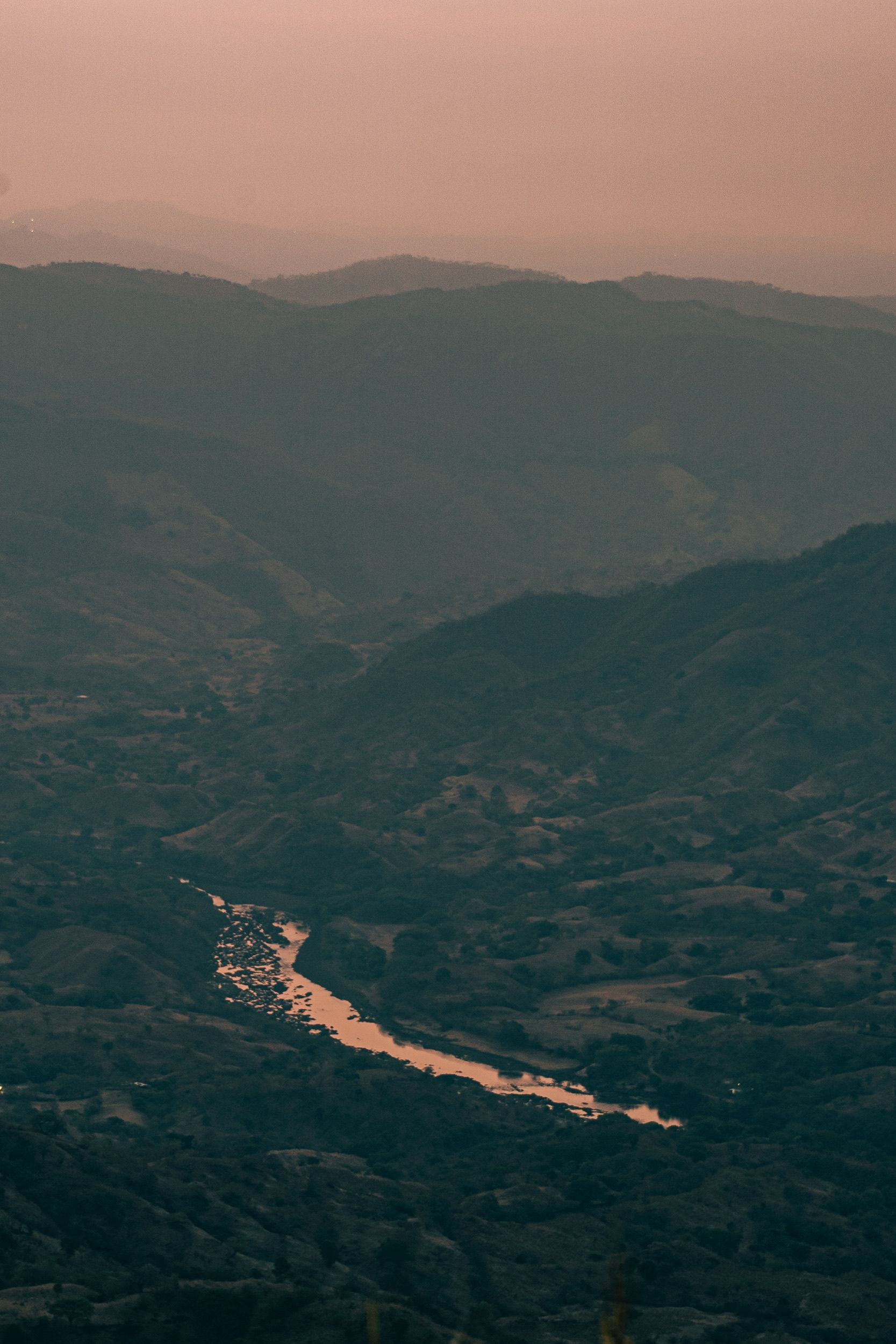 Fotomural Paisaje sereno del valle de Chalatenango con un río serpenteante al atardecer, destacando la belleza natural.