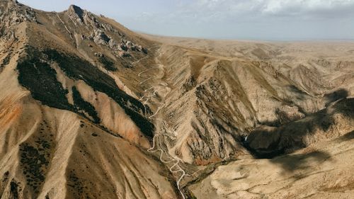 Free Aerial view of a zigzag road through Terskey Alatau mountains in Kyrgyzstan, showcasing rugged beauty. Stock Photo