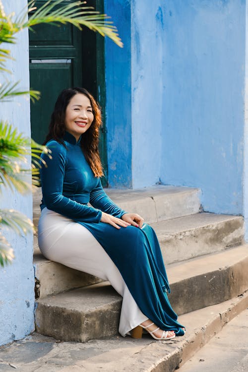 A Woman in a Blue Velvet Dress Sitting on Steps