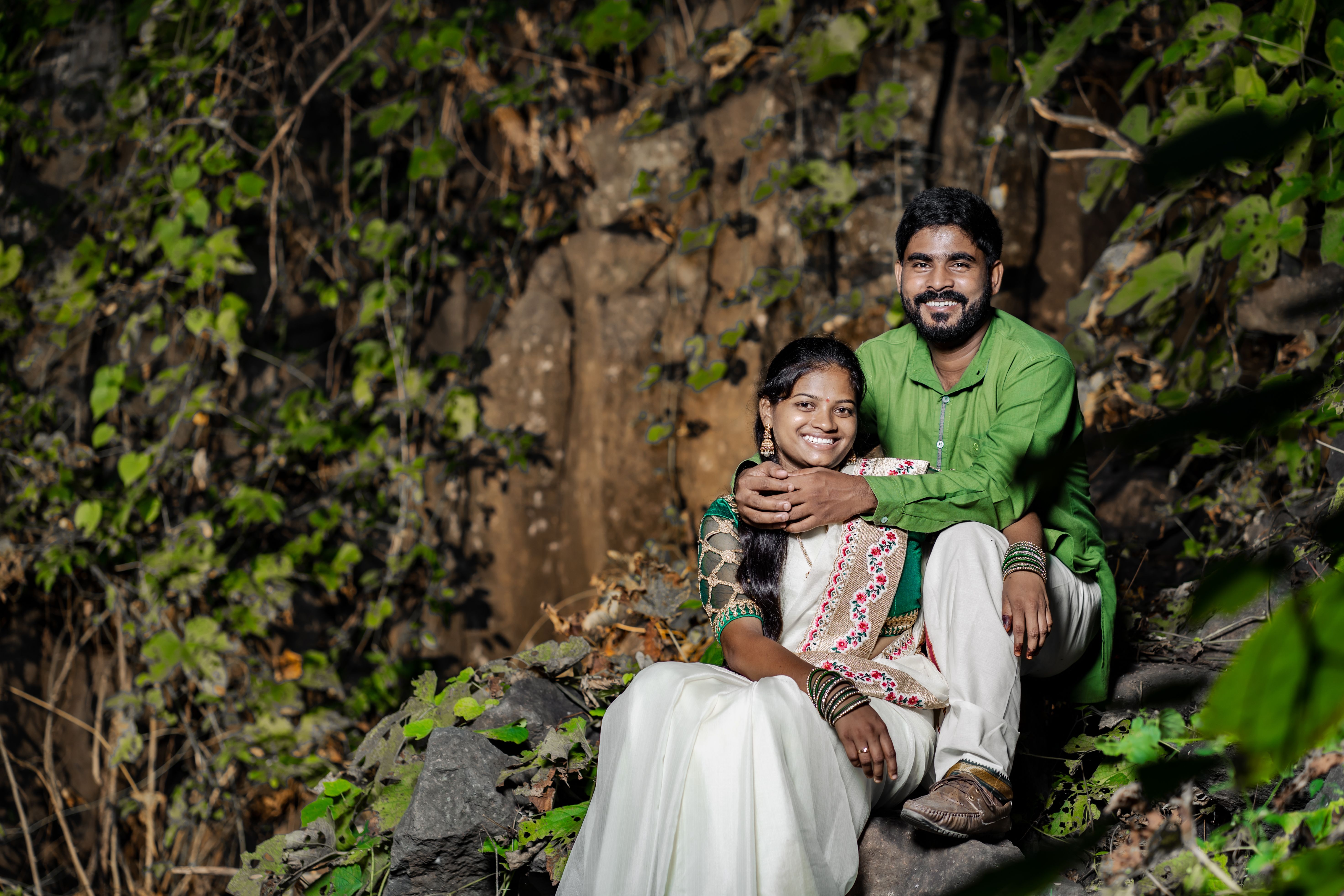 Smiling Couple in Traditional Clothing Sitting in Forest · Free Stock Photo