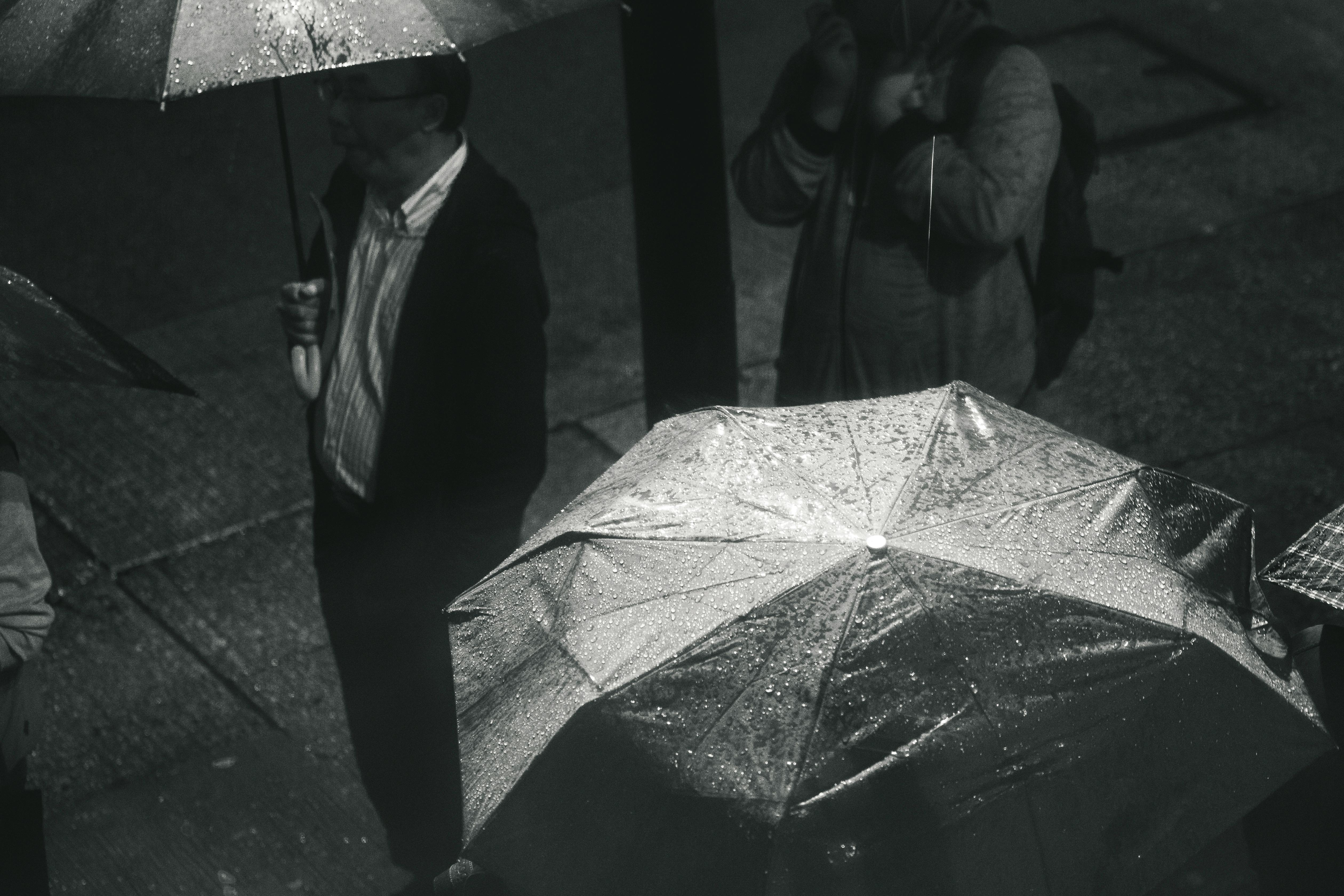 Greyscale Photo of Man Holding Umbrella While Raining · Free Stock Photo