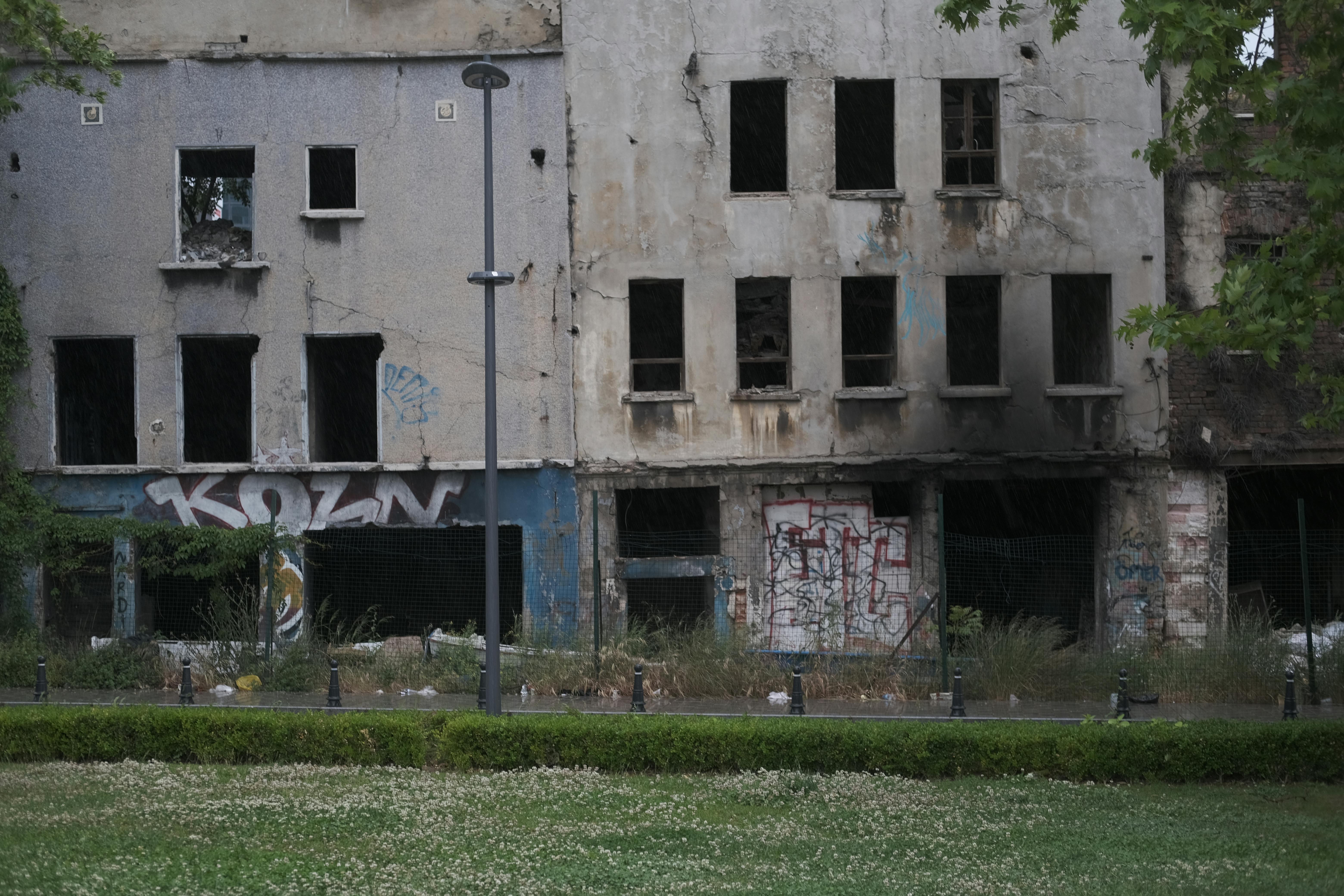 Weathered facade of a graffiti-covered building in an urban setting, showcasing decay.