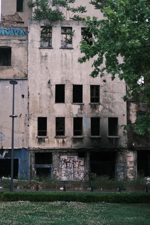 Free Abandoned building with graffiti and visible decay surrounded by greenery. Stock Photo