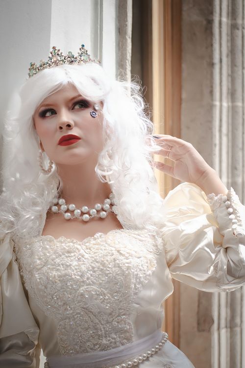 Free Elegant portrait of woman in a vintage white dress with crown and pearls, captured indoors. Stock Photo