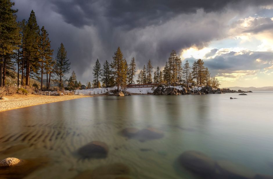 Capture of Lake Tahoe's tranquil waters under dramatic storm clouds at sunset, highlighting natural beauty.