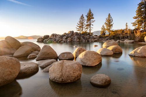 Free Peaceful view of Lake Tahoe with rocks and trees during sunset. Stock Photo