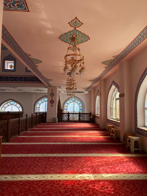 Free An elegant mosque interior showcasing chandeliers and detailed patterns with a red carpet floor. Stock Photo