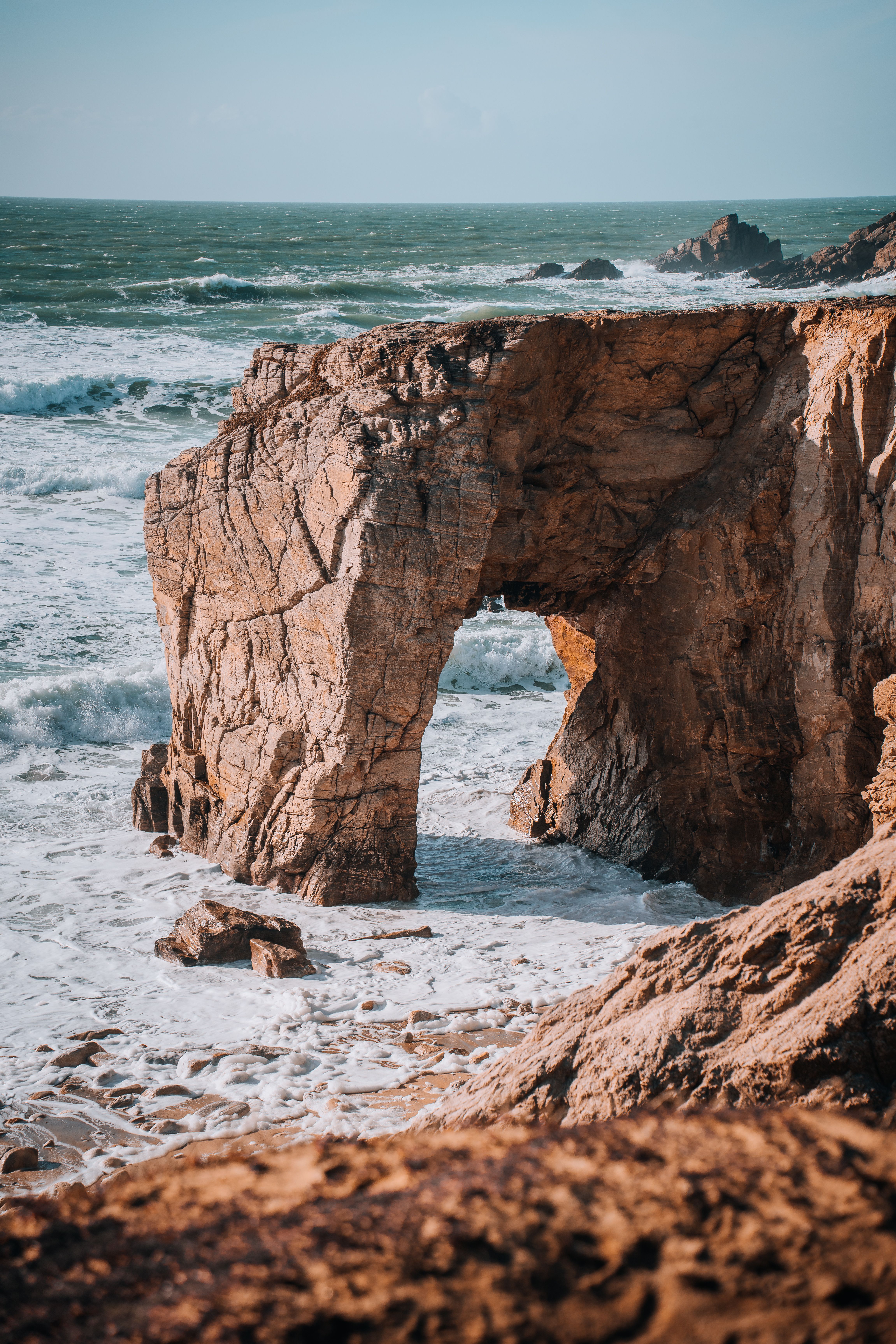 A rock formation in the ocean with waves crashing · Free Stock Photo