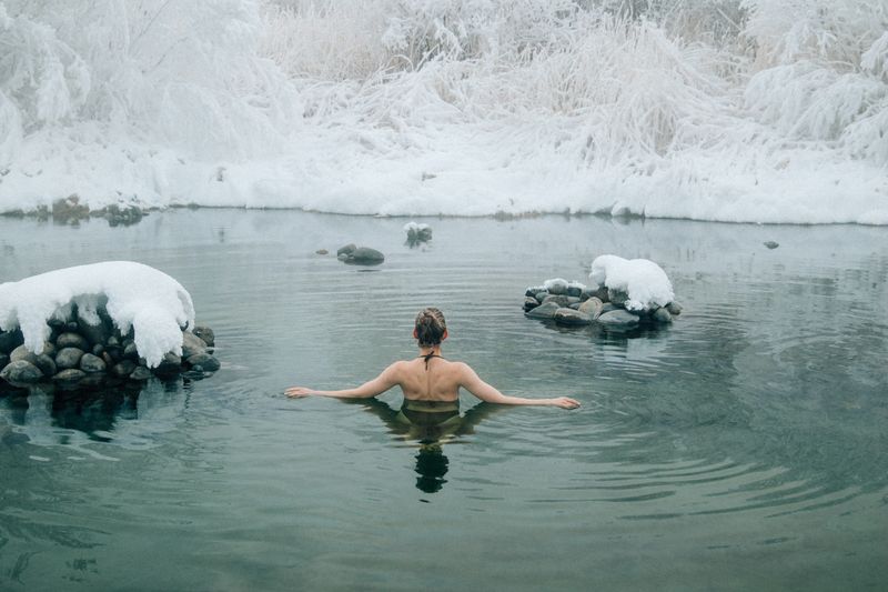 Person in cold water immersion during winter, embracing cold therapy in natural setting