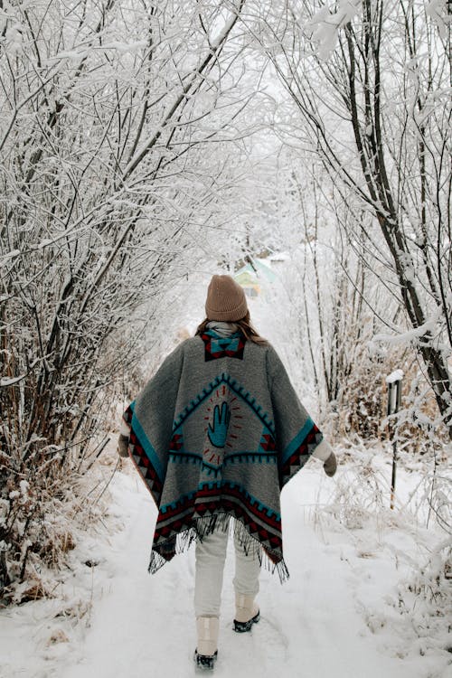 Girl in a poncho walk in winter forest
