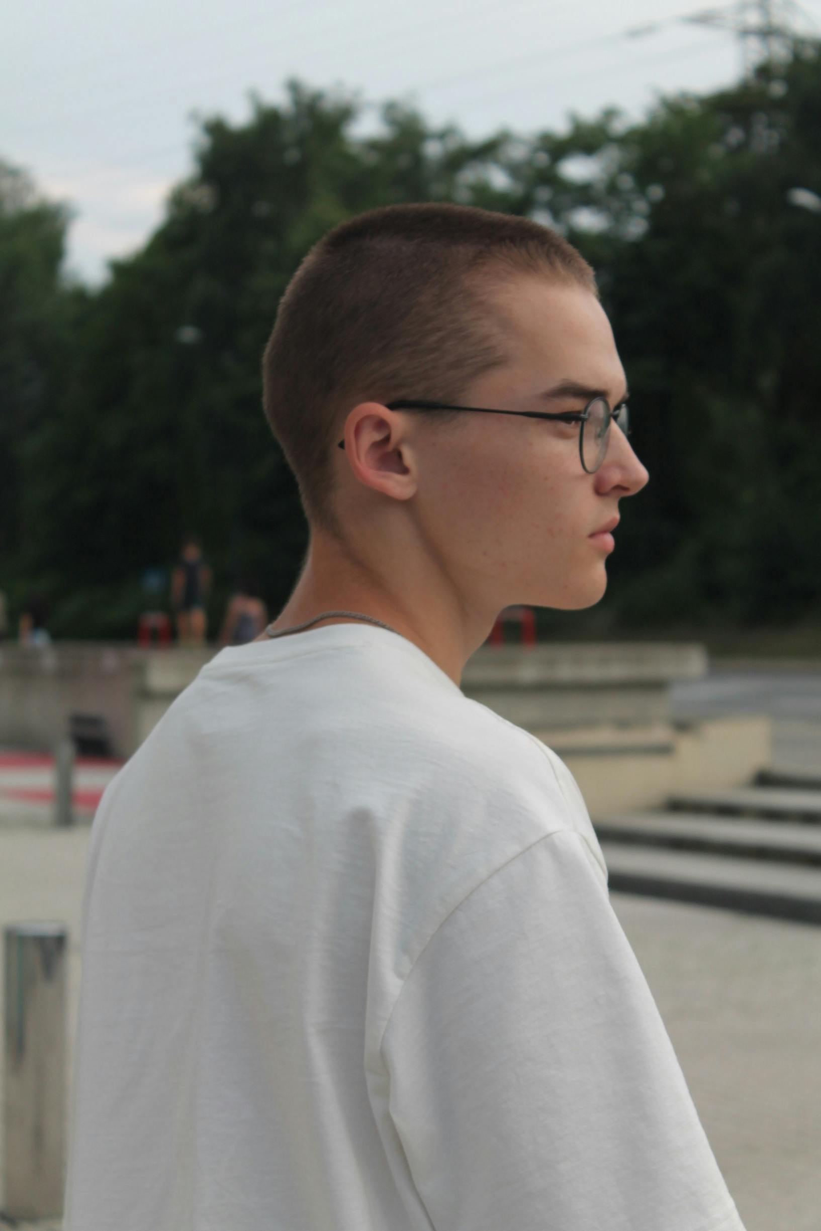 Side profile of a teenager wearing glasses in a modern urban environment.