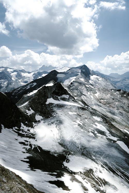 A view of a snowy mountain range with clouds