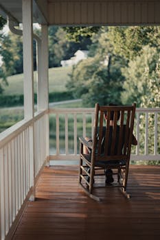 A serene view from a country porch with a cozy wooden rocking chair overlooking the countryside.