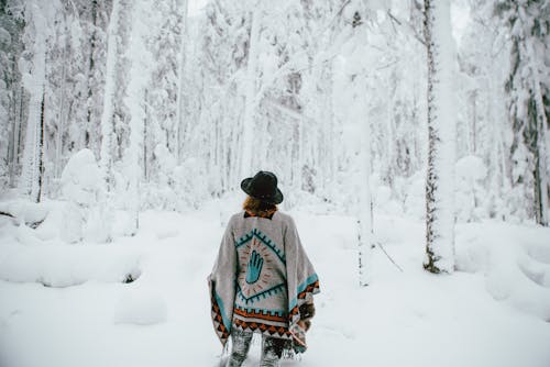 穿着雨披在冬季森林中行走的女人