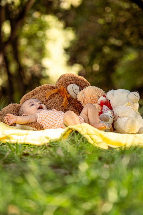 Free A baby laying on a blanket with a teddy bear Stock Photo