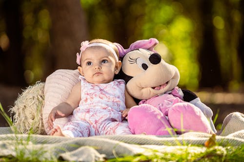 Free A baby girl sitting on the ground with a stuffed minnie mouse Stock Photo