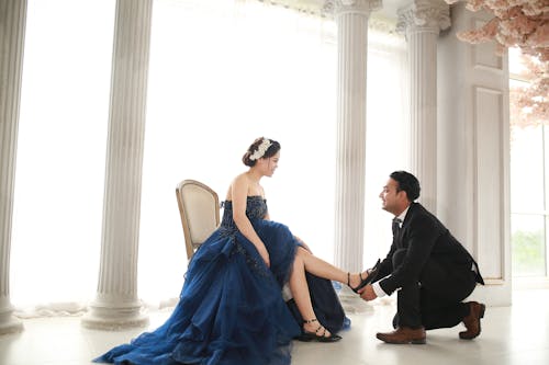 A man kneeling down to a woman in a blue dress