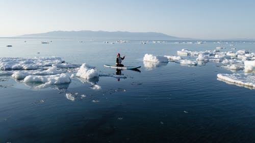 View of a Person Kayaking on a Sea between Ice Sheets 