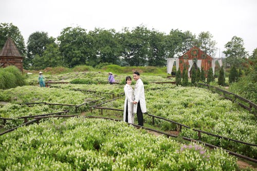 A couple in white wedding attire standing in a garden