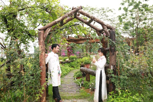 A man and woman standing in front of a wooden archway