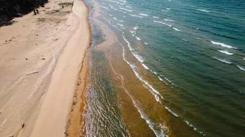 Free A stunning aerial view capturing the tranquil meeting of sand and sea on a remote coast. Stock Photo