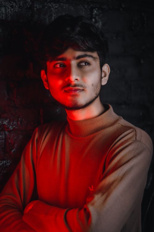 Free Portrait of a young man with a contemplative look in red moody lighting, studio shoot. Stock Photo