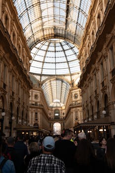 Stunning view of Galleria Vittorio Emanuele II's glass dome and bustling tourists in Milan, Italy.